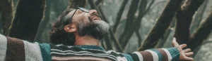 Hombre con los brazos abiertos, ojos cerrados y una gran sonrisa, expresando libertad y bienestar durante un proceso de técnica de transformación personal
