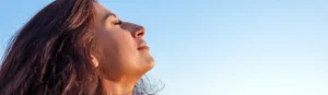 Mujer con los ojos cerrados y la cabeza inclinada hacia atrás durante un momento de conexión interior y expansión de conciencia.